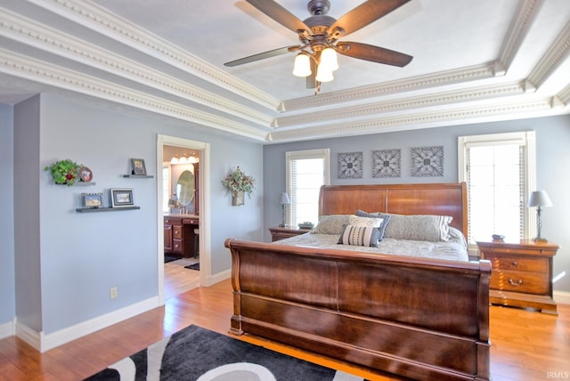 bedroom with a tray ceiling, baseboards, light wood-style floors, and ornamental molding