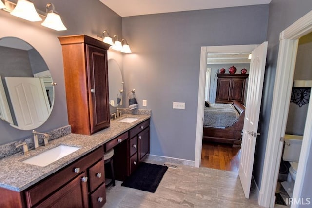 full bath featuring double vanity, toilet, ensuite bathroom, and a sink