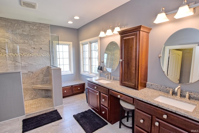 full bath featuring double vanity, visible vents, walk in shower, and a sink