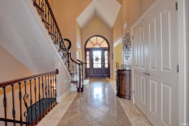 foyer with visible vents, baseboards, a high ceiling, and stairway