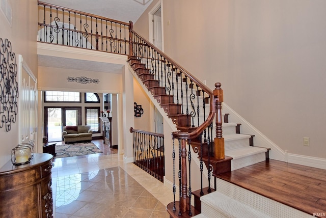 entryway featuring stairway, baseboards, a high ceiling, and wood finished floors