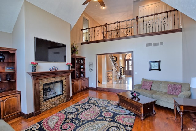 living area with visible vents, high vaulted ceiling, hardwood / wood-style floors, baseboards, and ceiling fan