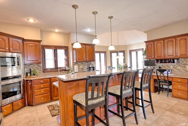 kitchen featuring a kitchen island, brown cabinets, stainless steel appliances, and a breakfast bar area