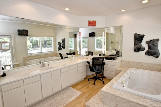 bathroom with recessed lighting, a garden tub, wood finished floors, and vanity