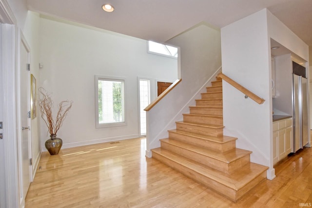 staircase featuring recessed lighting, wood finished floors, and baseboards