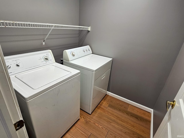 clothes washing area featuring washer and dryer, baseboards, light wood-style flooring, and laundry area