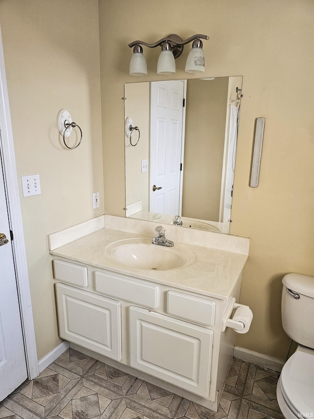 bathroom with baseboards, toilet, and vanity