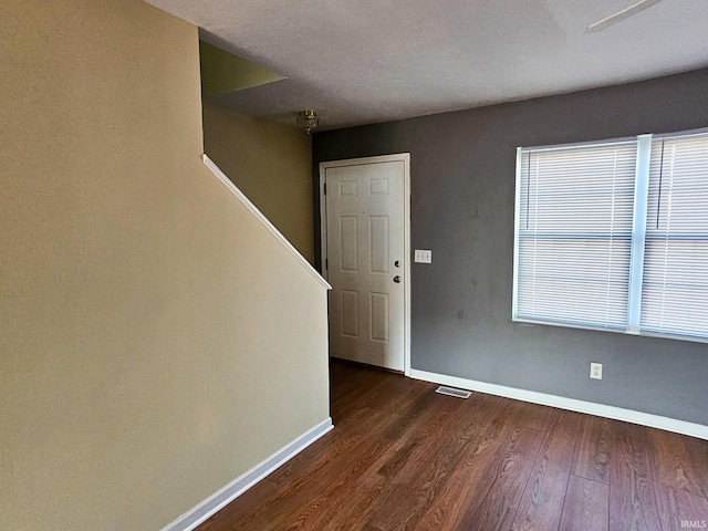 entryway featuring dark wood finished floors, stairs, visible vents, and baseboards