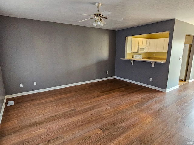 unfurnished living room with a textured ceiling, baseboards, a ceiling fan, and wood finished floors