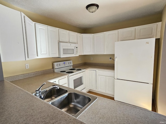 kitchen with white appliances, white cabinetry, and a sink