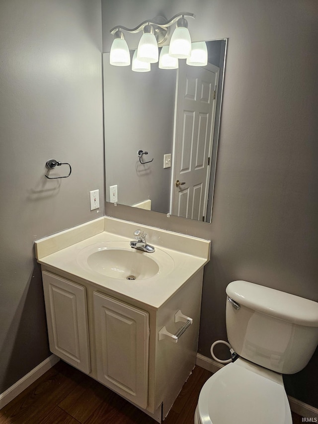 half bathroom featuring baseboards, toilet, wood finished floors, and vanity