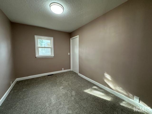 carpeted spare room with baseboards and a textured ceiling