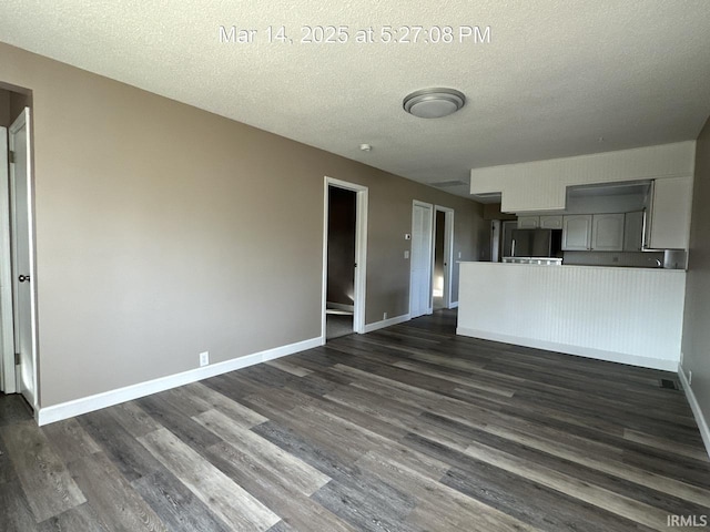 unfurnished living room featuring dark wood finished floors, baseboards, and a textured ceiling