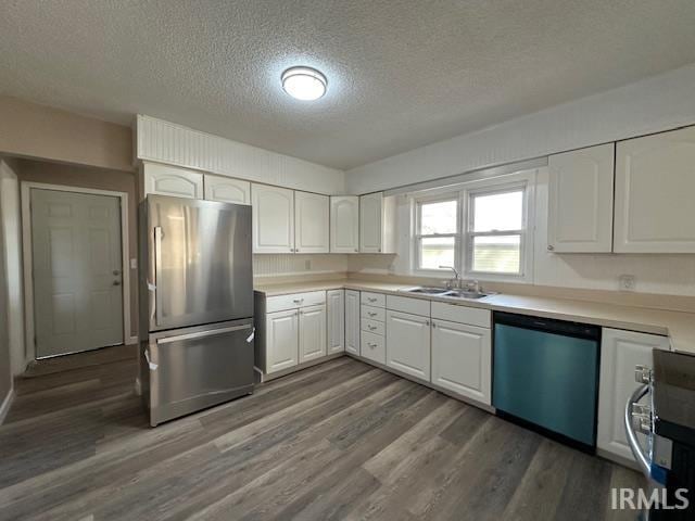 kitchen with a sink, dark wood finished floors, freestanding refrigerator, white cabinets, and dishwashing machine