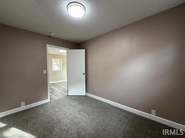 carpeted spare room featuring a textured ceiling and baseboards