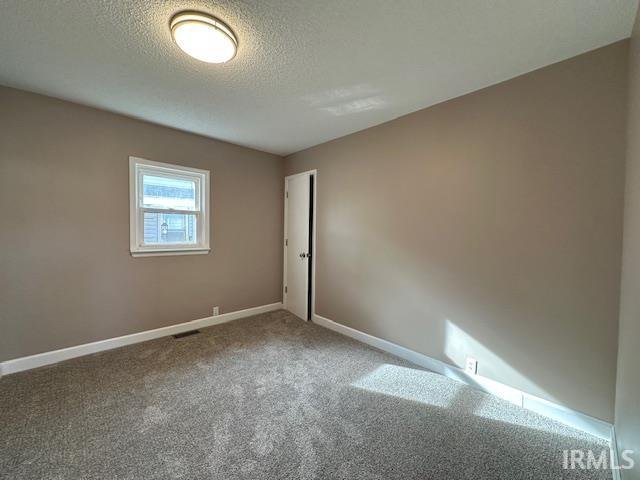 carpeted empty room with visible vents, a textured ceiling, and baseboards