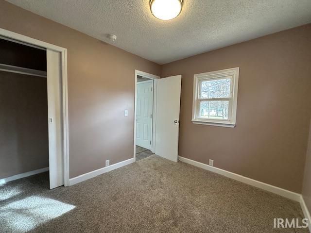 unfurnished bedroom featuring carpet flooring, a textured ceiling, and baseboards