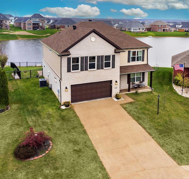 traditional-style home with a residential view, central air condition unit, an attached garage, and a water view