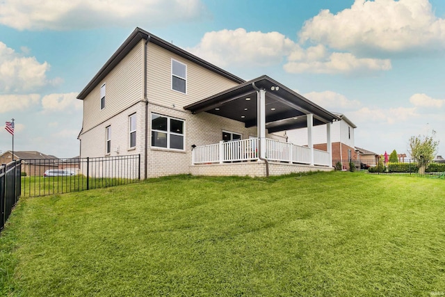 rear view of house with a yard, brick siding, and fence