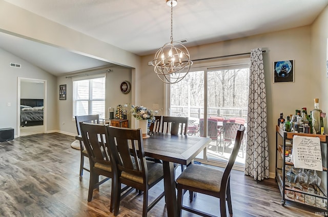 dining area featuring visible vents, baseboards, lofted ceiling, wood finished floors, and a notable chandelier