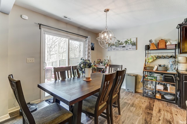 dining area with visible vents, baseboards, a notable chandelier, and light wood-style flooring