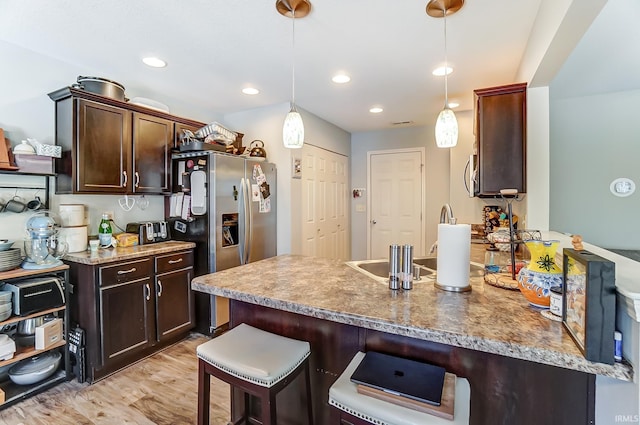 kitchen featuring pendant lighting, a kitchen bar, dark brown cabinets, and a peninsula