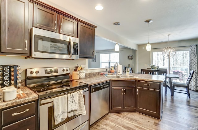 kitchen featuring dark brown cabinetry, a peninsula, stainless steel appliances, and a sink