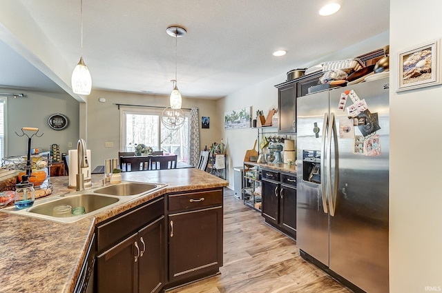 kitchen featuring pendant lighting, a sink, stainless steel fridge with ice dispenser, light wood finished floors, and dark brown cabinets