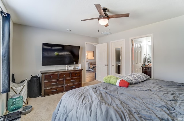 carpeted bedroom featuring visible vents, ensuite bath, and a ceiling fan