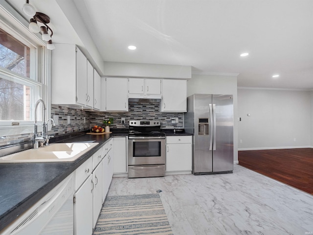 kitchen featuring dark countertops, decorative backsplash, stainless steel appliances, white cabinetry, and a sink