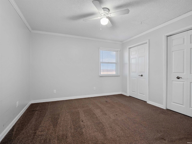 unfurnished bedroom featuring dark colored carpet, baseboards, a textured ceiling, and ornamental molding