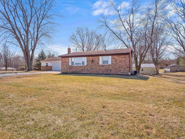 view of front of home with brick siding, a front yard, a chimney, a garage, and driveway