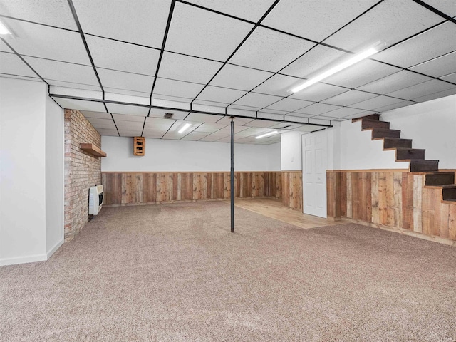 finished basement with stairway, carpet flooring, wood walls, and wainscoting