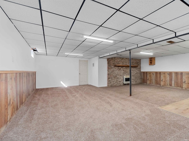 finished below grade area featuring wainscoting, wooden walls, a drop ceiling, and carpet floors