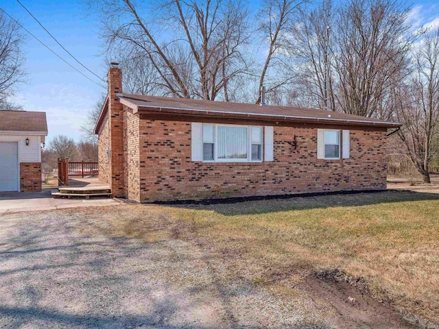 view of property exterior with a yard, a wooden deck, a garage, brick siding, and a chimney