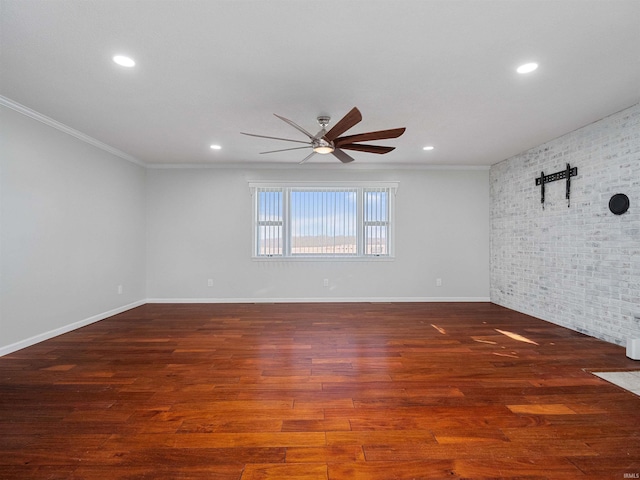 spare room featuring brick wall, crown molding, baseboards, ceiling fan, and wood finished floors