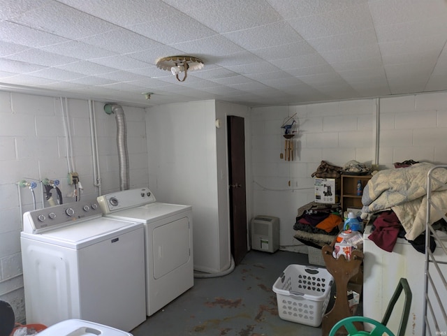 washroom featuring laundry area, concrete block wall, and independent washer and dryer