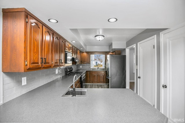 kitchen featuring brown cabinets, a sink, recessed lighting, appliances with stainless steel finishes, and decorative backsplash