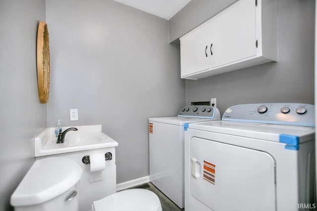 washroom with laundry area, separate washer and dryer, baseboards, and a sink