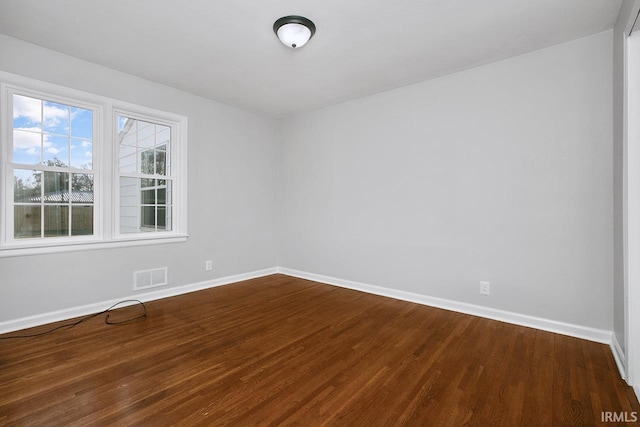 unfurnished room with dark wood finished floors, baseboards, and visible vents