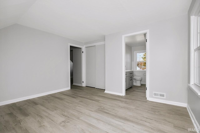 unfurnished bedroom with visible vents, baseboards, ensuite bath, light wood-style floors, and a closet