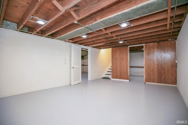 finished basement featuring stairway and concrete block wall