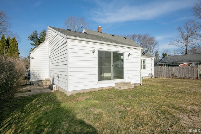 rear view of house with a yard, fence, and a chimney