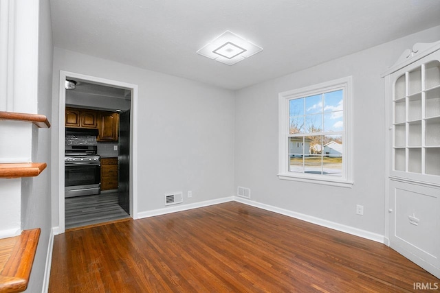 empty room featuring visible vents, baseboards, and dark wood finished floors