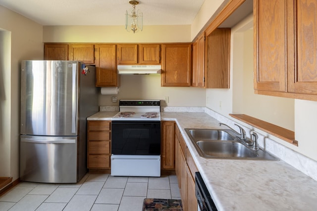 kitchen with freestanding refrigerator, a sink, electric range oven, under cabinet range hood, and brown cabinets