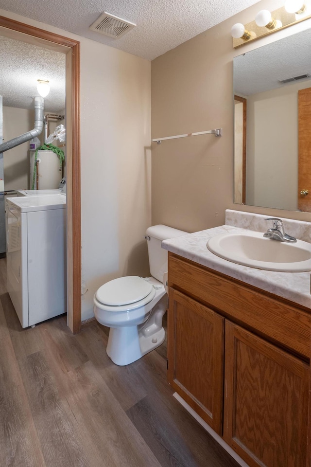 bathroom featuring visible vents, washer / clothes dryer, a textured ceiling, and wood finished floors