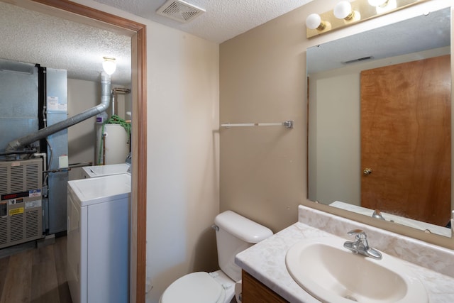 bathroom with heating unit, visible vents, washer / clothes dryer, a textured ceiling, and toilet