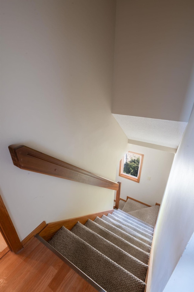 staircase with baseboards and wood finished floors