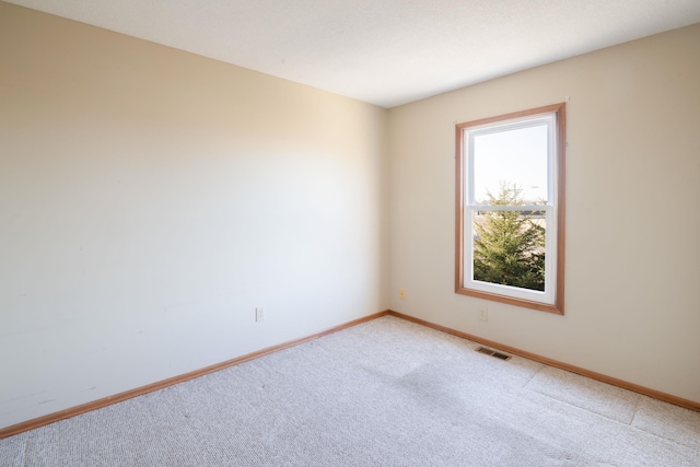 empty room with light colored carpet, visible vents, and baseboards