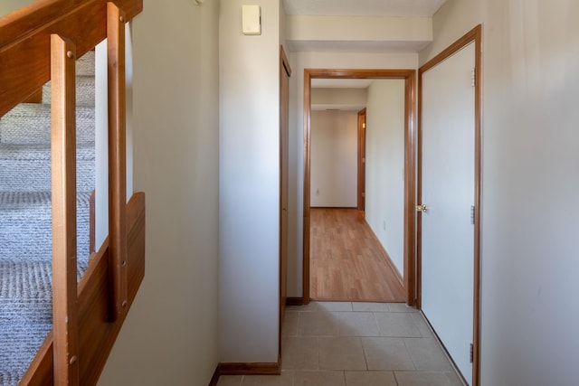 hall featuring light tile patterned floors and baseboards